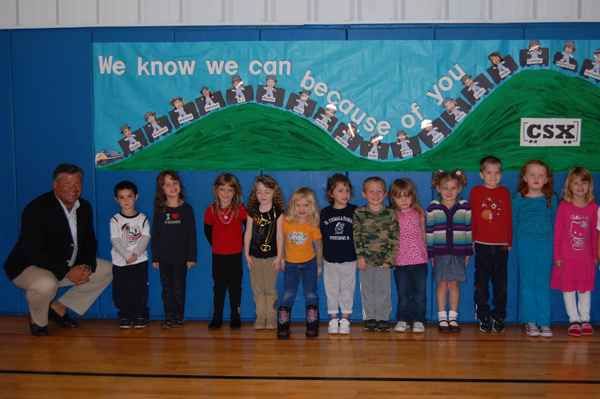 Students at Ss. Cosmas and Damian School with a CSX representative in front of a 'We know we can because of you' display