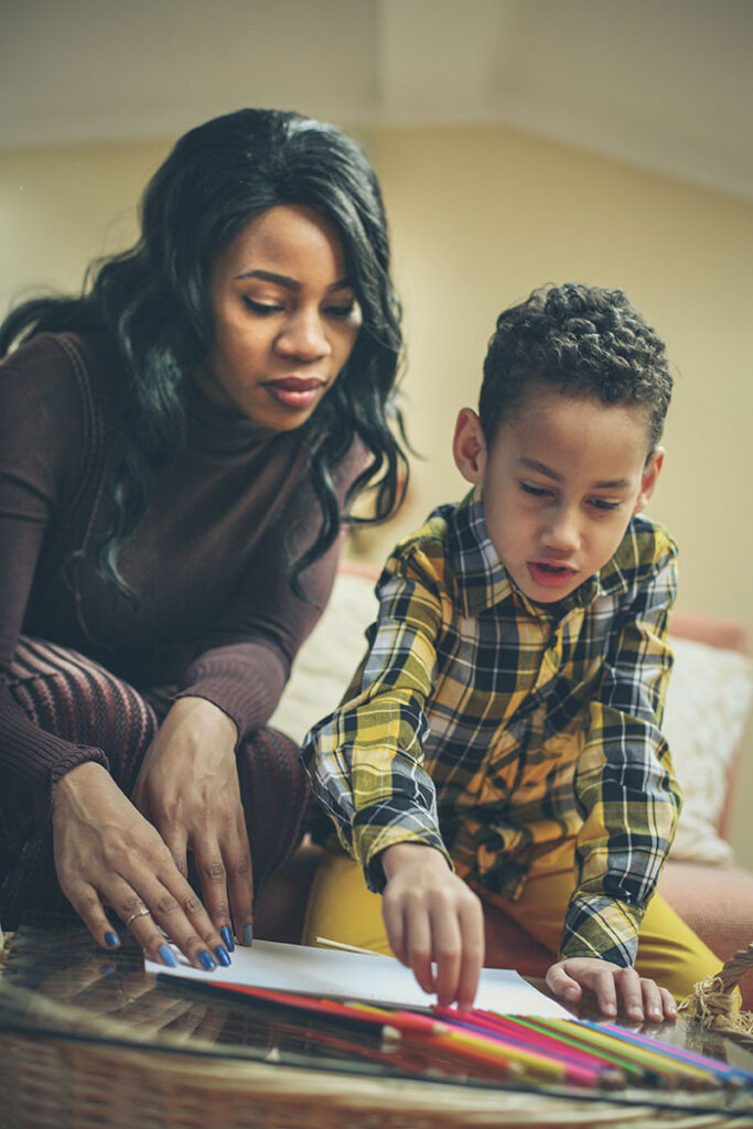 Mother and son drawing together with colored pencils at home